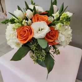 Compact bouquet of orange roses and white blooms in a clear glass vase
