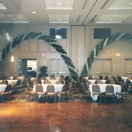 Balloon arches over round tables in a banquet hall