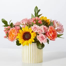 Pink roses and sunflowers arranged in a striped vase