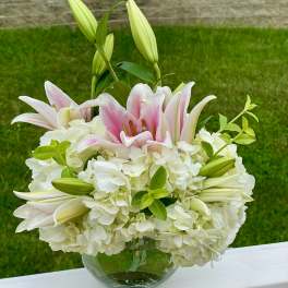 Pink lilies and white hydrangeas in a glass bowl vase
