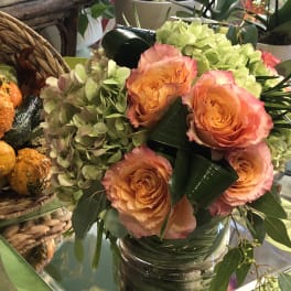 Peach roses and pale green hydrangeas in a glass vase