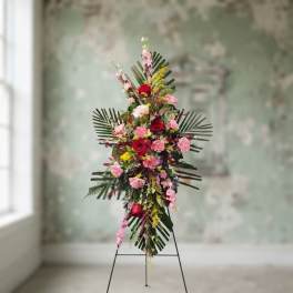 Tall floral standing spray with pink and red flowers on an easel