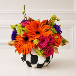 Bright bouquet of orange gerbera daisies and pink roses in a black-and-white vase