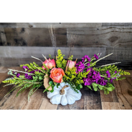 Low floral arrangement in a white pumpkin vase with pink roses and purple flowers