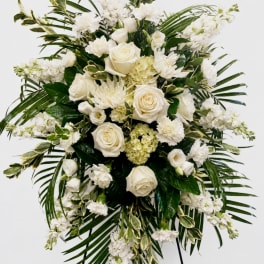 White rose and carnation arrangement with palm fronds on a stand