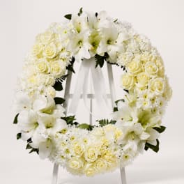 White floral wreath with roses and lilies on a stand