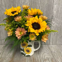 Sunflower and peach daisy arrangement in a white mug vase