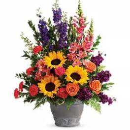 Colorful mixed flower arrangement in a gray vase with sunflowers and roses