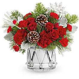 Red roses and carnations in a clear glass vase with pinecones
