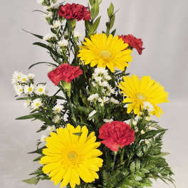 Mixed yellow and red flowers arranged in a mug labeled Get Well