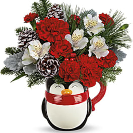 Holiday bouquet in a penguin mug with red and white flowers