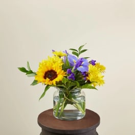 Sunflowers and purple flowers arranged in a clear glass vase