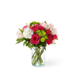 Mixed bouquet of hot pink, white, and green flowers arranged in a clear glass cylinder vase