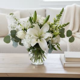 White lilies and roses arranged in a clear glass vase