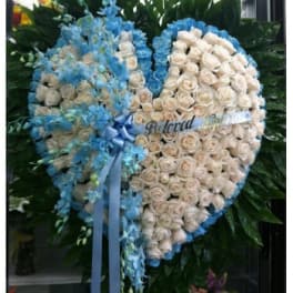Heart-shaped floral wreath of white roses and blue flowers with a ribbon