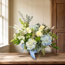 Blue and white floral arrangement in a vase with a ribbon