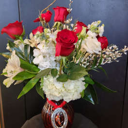 Red roses and white flowers arranged in a glass vase