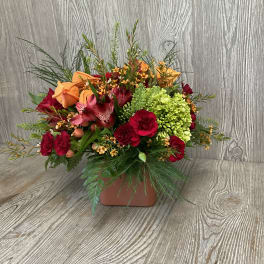Mixed bouquet of red and orange flowers in a square vase