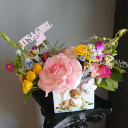 Mixed flower arrangement in a white teddy bear vase with a pink name topper