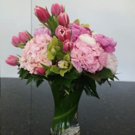 Pink tulips and hydrangeas arranged in a clear glass vase