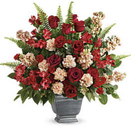 Red roses and carnations arranged in a gray urn vase