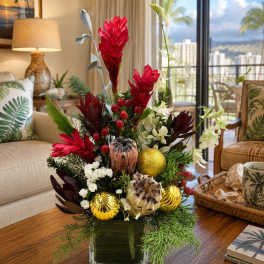Tropical floral arrangement in a square glass vase with red and white blooms