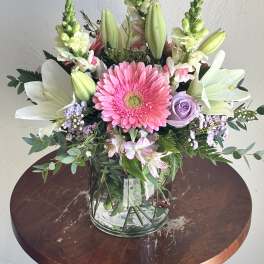 Pink gerbera bouquet with white lilies and lavender roses in a glass vase