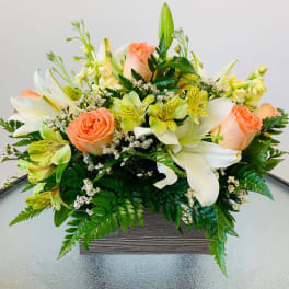 Peach roses and white lilies in a low rectangular container