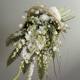 White floral basket arrangement with cascading blooms and a wicker handle
