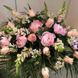 Pink roses and peonies arranged with snapdragons and greenery