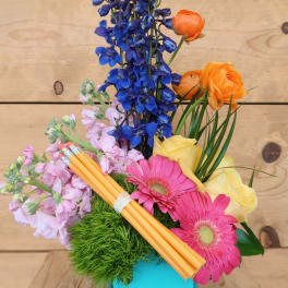 Colorful bouquet in a turquoise vase with blue, pink, yellow, and orange flowers