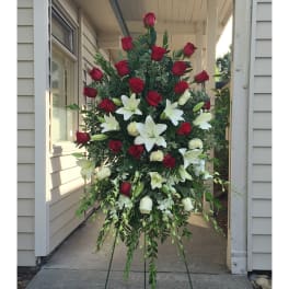 Standing floral spray of red roses and white lilies on an easel