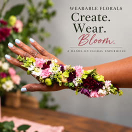 Hands wearing a floral wrist cuff with pink, white, and green flowers
