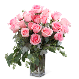 Pink roses arranged in a clear glass vase with greenery