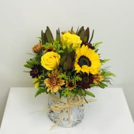 Yellow roses and sunflowers in a rustic wrapped vase arrangement