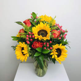 Bouquet of sunflowers and red roses in a clear glass vase