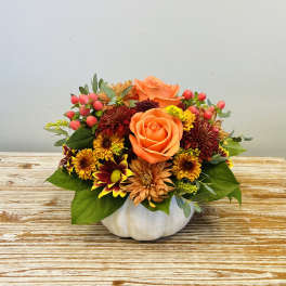 Orange roses and mixed fall flowers arranged in a white pumpkin container