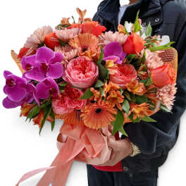 Large bouquet of pink, orange, and purple flowers wrapped with a satin ribbon