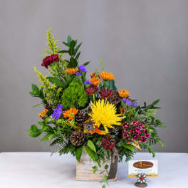 Mixed flower arrangement in a square vase with bright yellow, orange, purple, and pink blooms