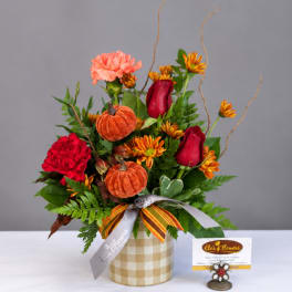 Fall bouquet with red roses, carnations, and orange mums in a plaid container