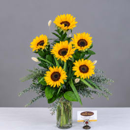 Sunflower arrangement in a clear glass vase with greenery