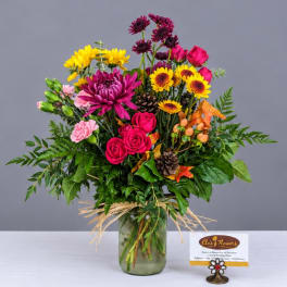 Mixed bouquet of pink, yellow, and purple flowers in a glass vase