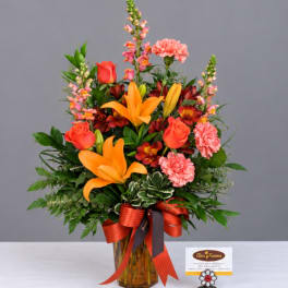 Mixed bouquet in an amber glass vase with orange lilies, roses, and pink carnations