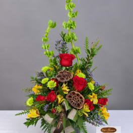 Tall mixed flower arrangement with red roses and yellow blooms in a vase