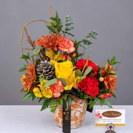 Colorful mixed flower arrangement in a patterned pot with a ribbon
