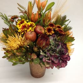 Autumn bouquet with lilies, chrysanthemums, apples, and hydrangea in a textured vase