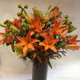 Orange lilies arranged in a tall black vase