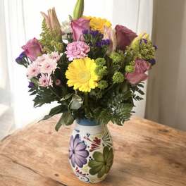 Mixed bouquet in a painted ceramic vase with pink, yellow, and purple flowers