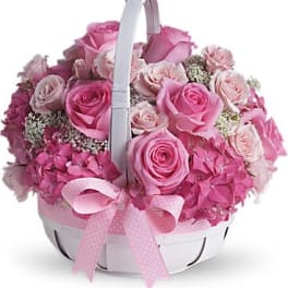 Pink roses and hydrangeas in a white basket with a ribbon