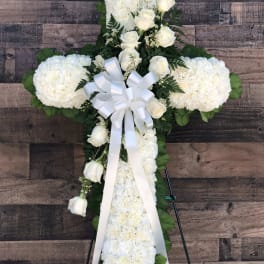 White floral cross with roses and ribbon on an easel